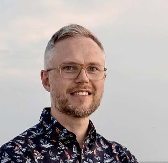 Portrait of Jon Olav Eikenes, a white man with grey hair, glasses and short beard